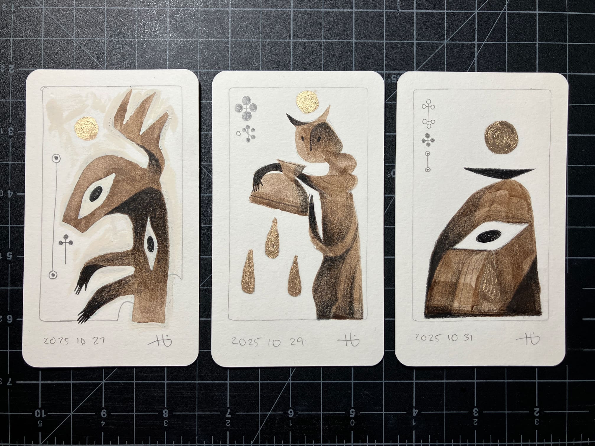 Three tarot-size cards, each with a drawing made in brown ink and graphite, with a little gold paint used for reflective materials such as halos. From left to right, they are an abstract winged entity, a horned figure pouring out a bowl, and an altar with a single eye.